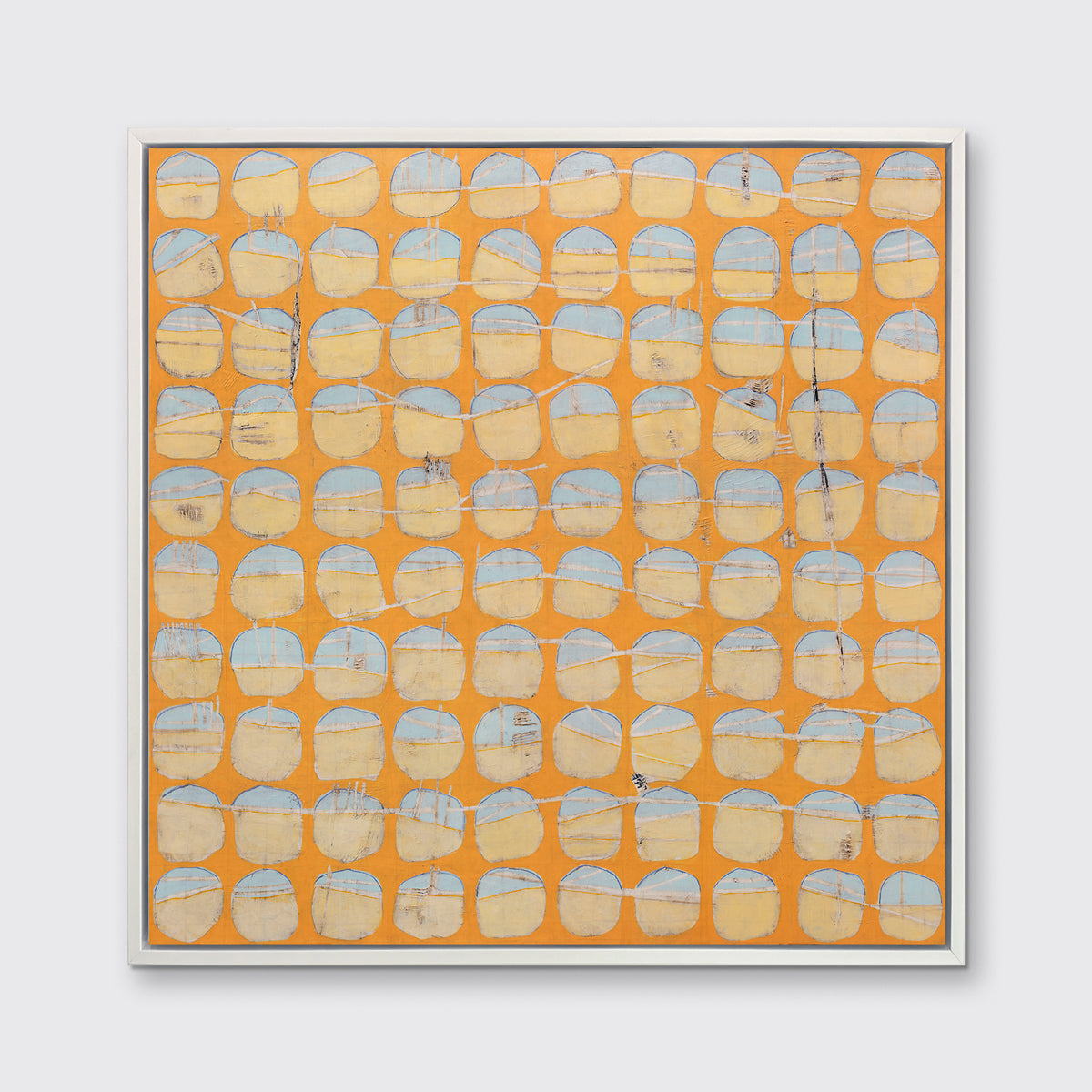 An orange and light blue abstract circle print in a white floater frame hangs on a white wall.