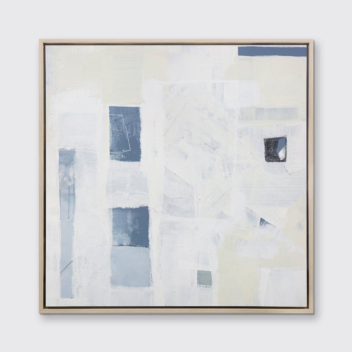 A white, pale yellow and slate blue abstract print in a white oak wood floater frame hangs on a white wall.