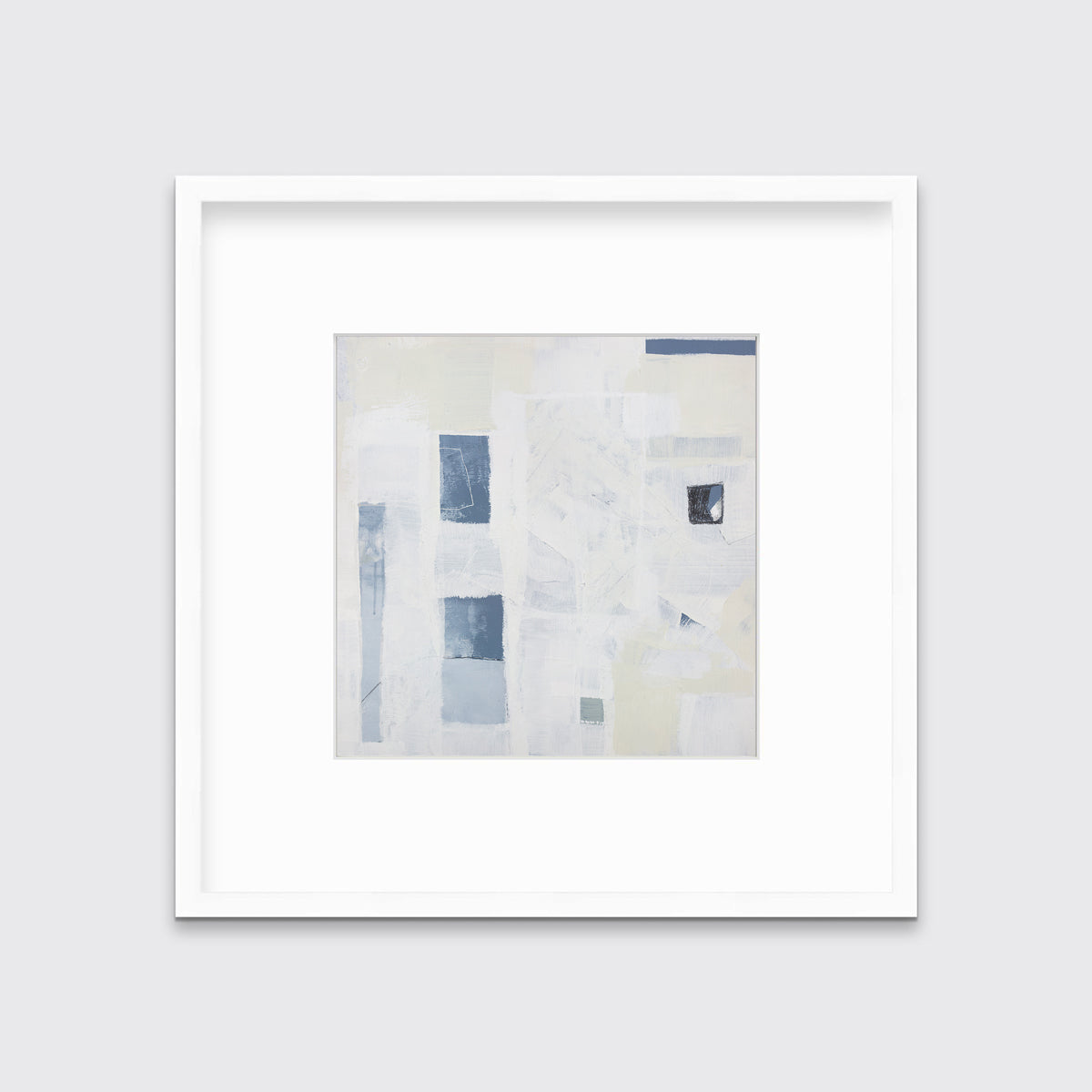 A white, pale yellow and slate blue abstract print in a white frame with a mat hangs on a white wall.