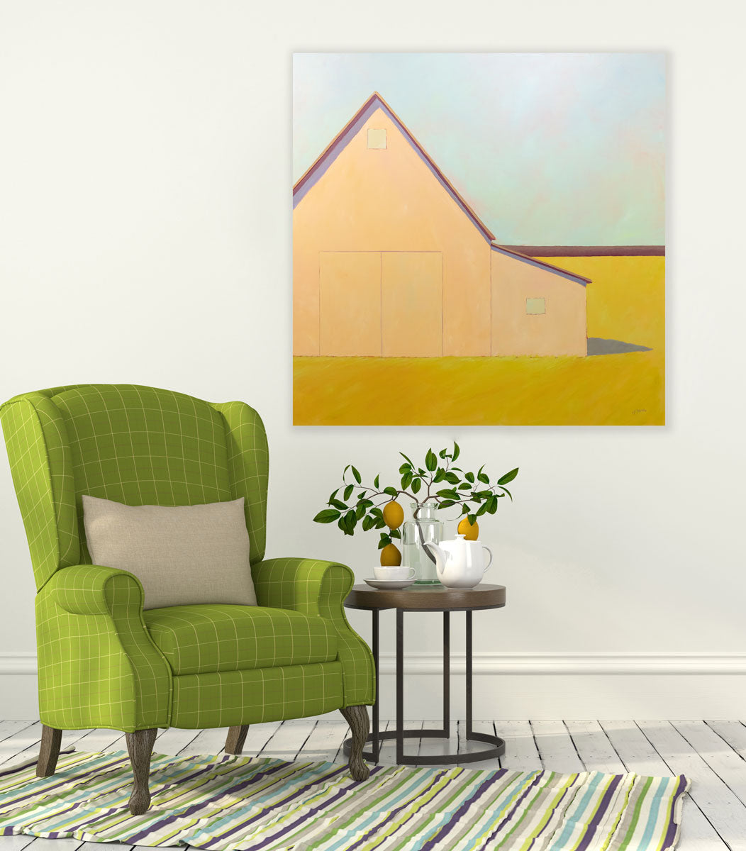 A painting is hung above a green armchair. In the painting a large, cream-colored barn sits in a yellow field. Wired and ready to hang.
