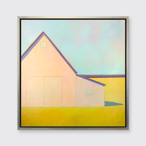 A light blue, coral and deep yellow landscape print of a barn in a silver floater frame hangs on a white wall.