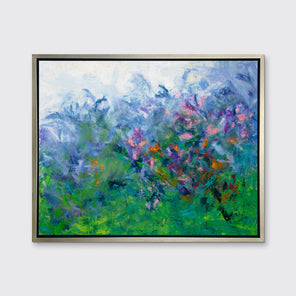 A multicolored abstract floral print in a silver floater frame hangs on a white wall.