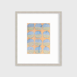 A orange, blue, green and white abstract print in a silver frame with a mat hangs on a white wall.