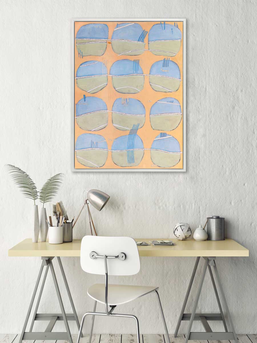 A orange, blue, green and white abstract print in a white floater frame hangs on a white wall above a desk with a small lamp, two white vases with fern leaves and a white chair.