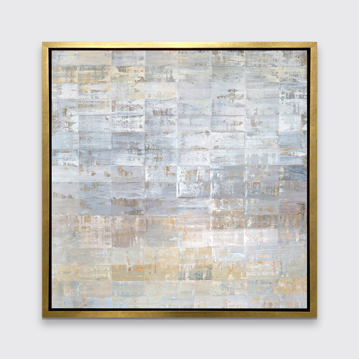 A grey, silver and light gold abstract geometric print in a gold floater frame hangs on a white wall.