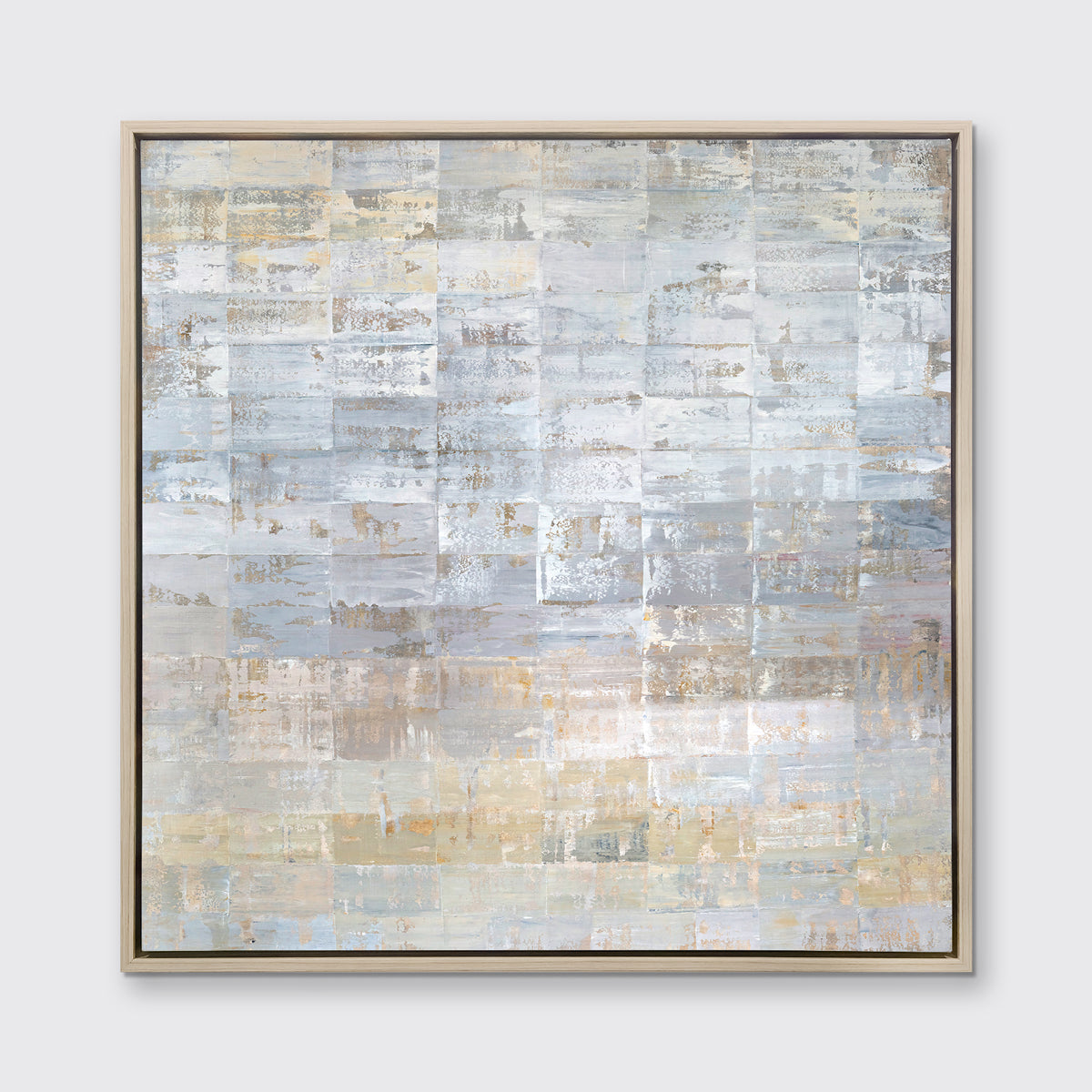 A grey, silver and light gold abstract geometric print in a white oak wood floater frame hangs on a white wall.