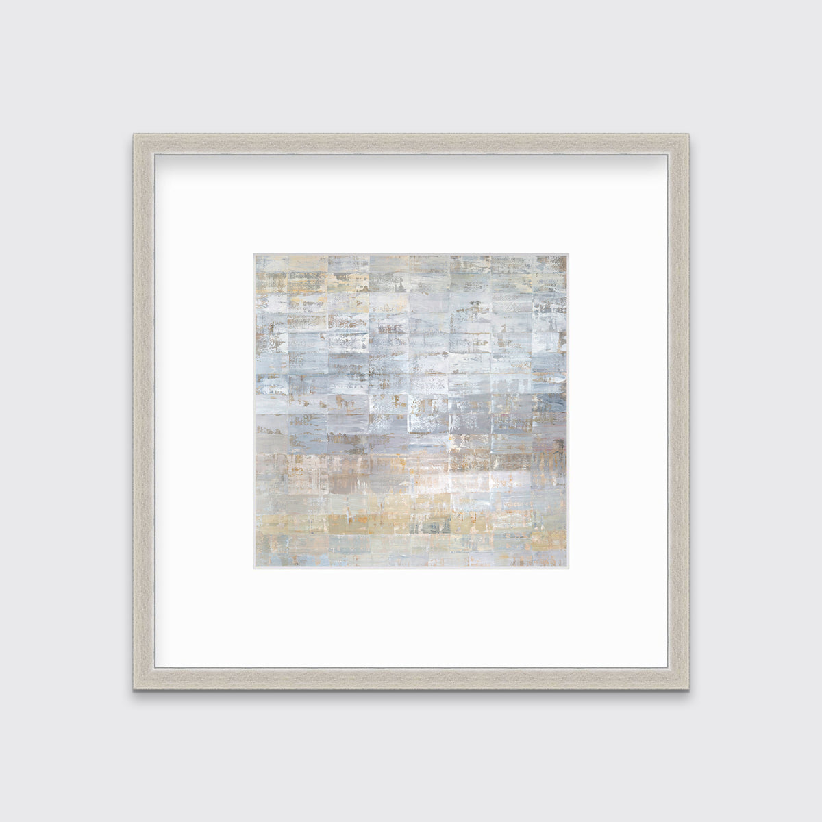 A grey, silver and light gold abstract geometric print in a silver frame with a mat hangs on a white wall.