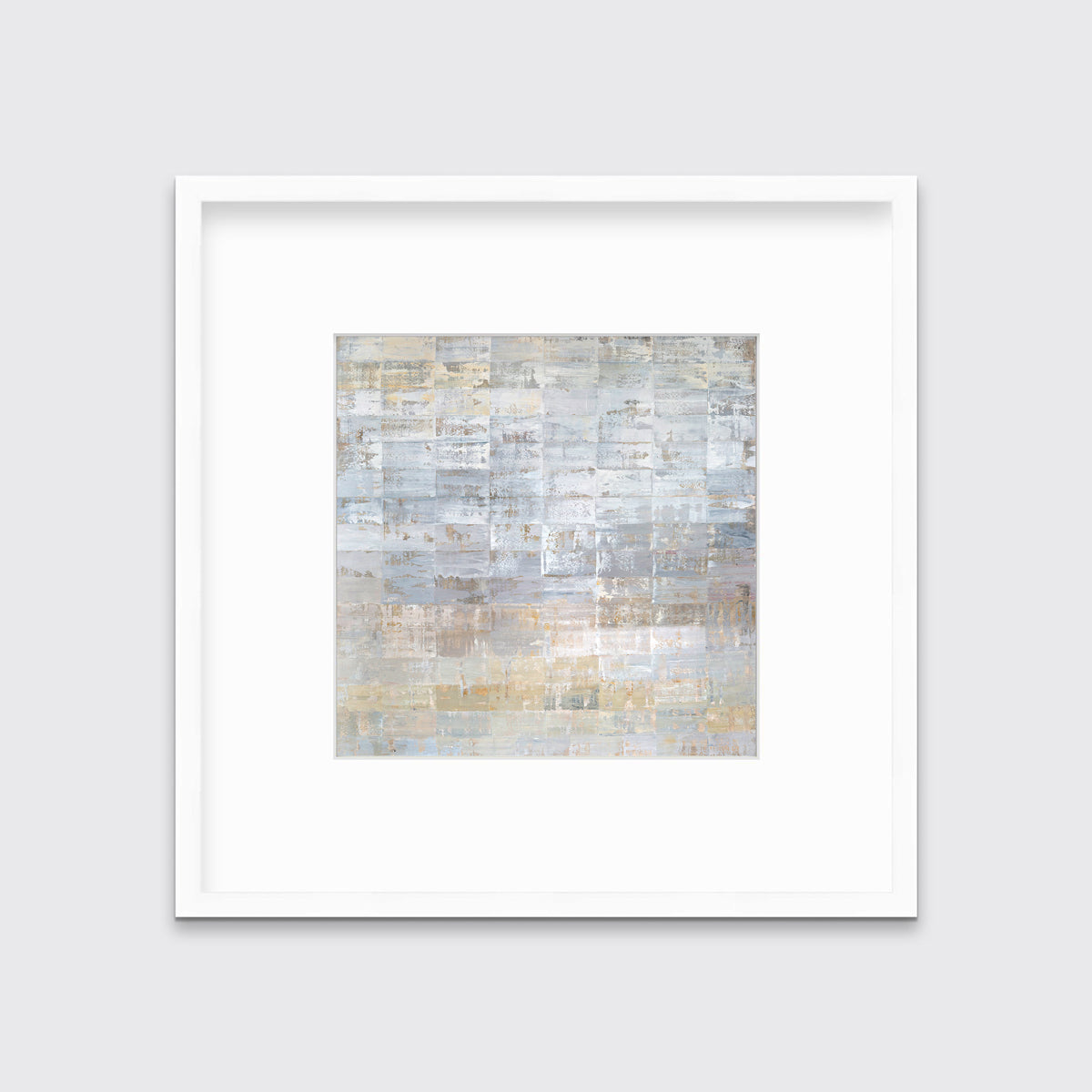 A grey, silver and light gold abstract geometric print in a white frame with a mat hangs on a white wall.