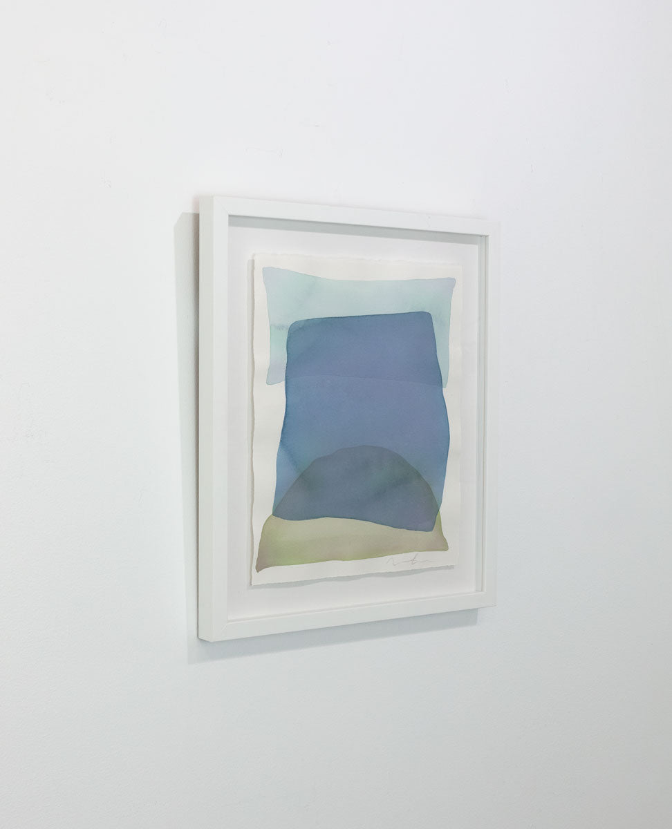 A watercolor of light azure, blue, and yellow forms overlapping is seen at an angle on a gallery wall. Wired and ready to hang.
