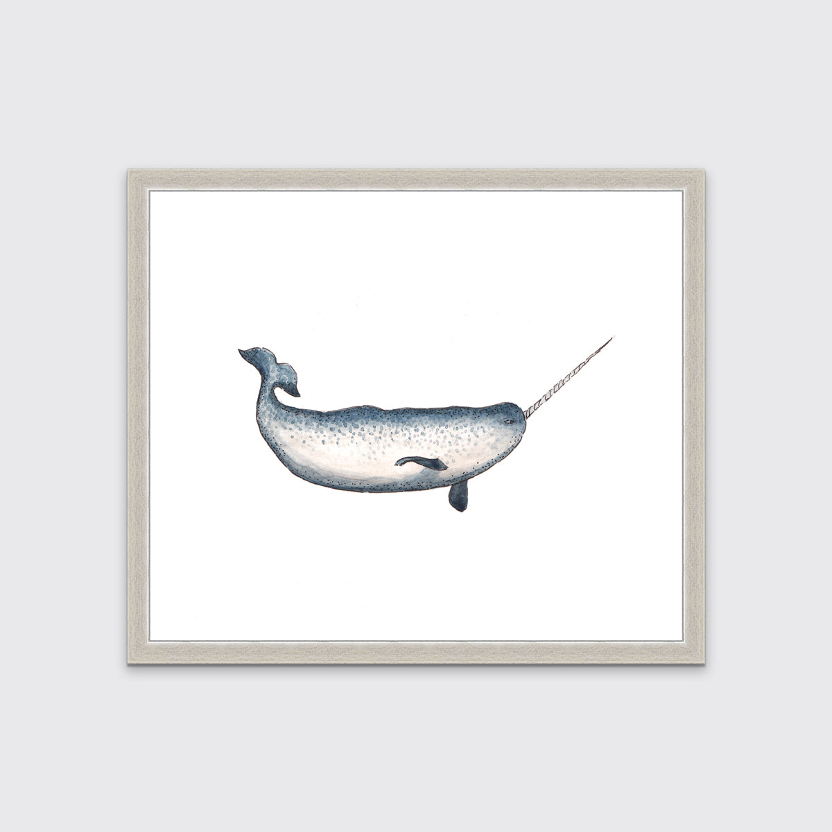 A blue and white narwhal print in an unmatted silver frame hangs on a white wall.