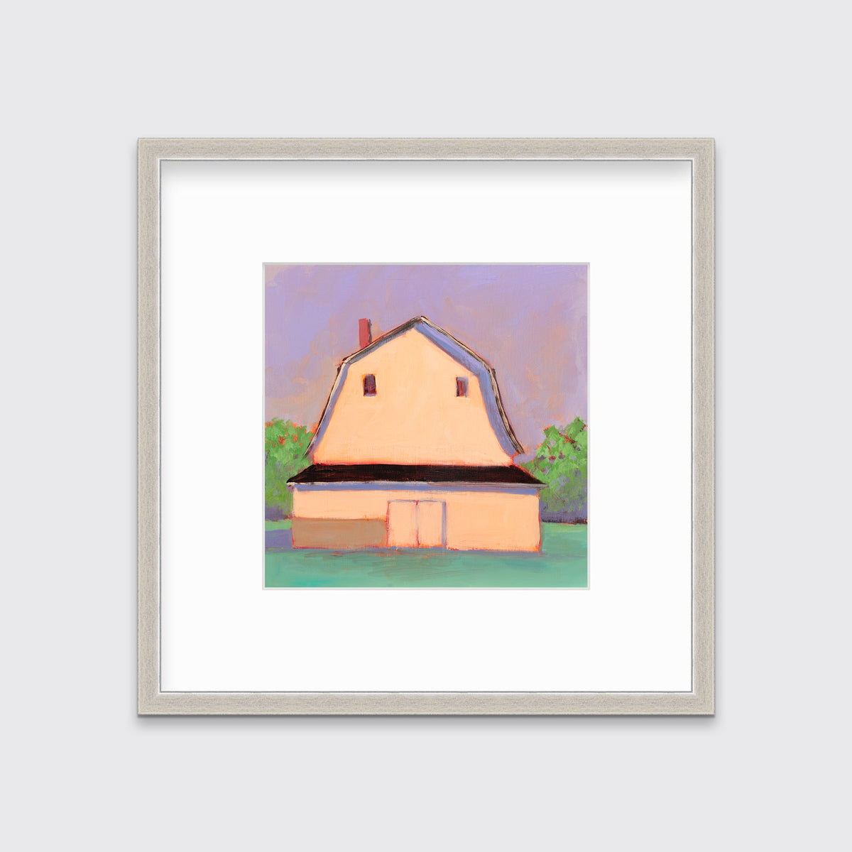 A print of a light orange barn, a lavender sky, green bushes and a teal ground in a silver frame with a mat hangs on a white wall.