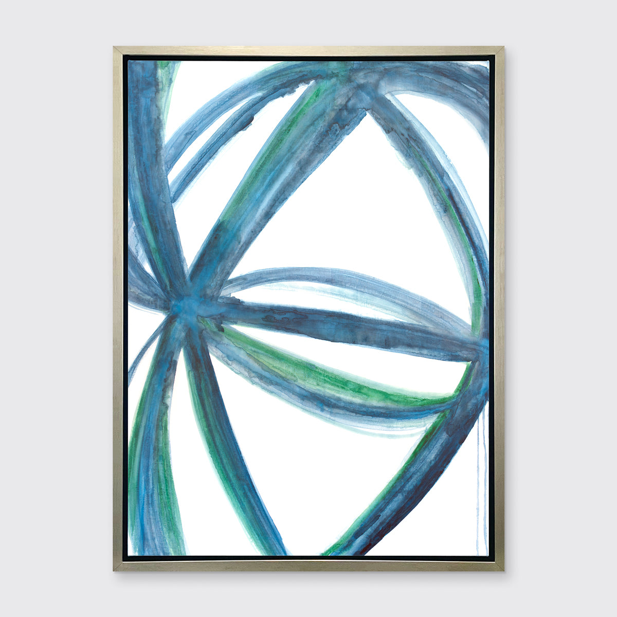 A blue, green, and white abstract print framed in a warm silver frame hangs on a light grey wall.