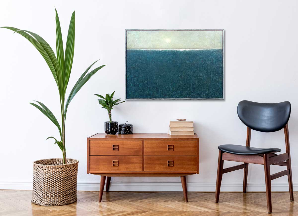 A blue and light green abstract landscape painting by Elwood Howell hangs on a white wall above a console cabinet with books and a small potted plant, a black chair and a large woven floor basket with a plant.