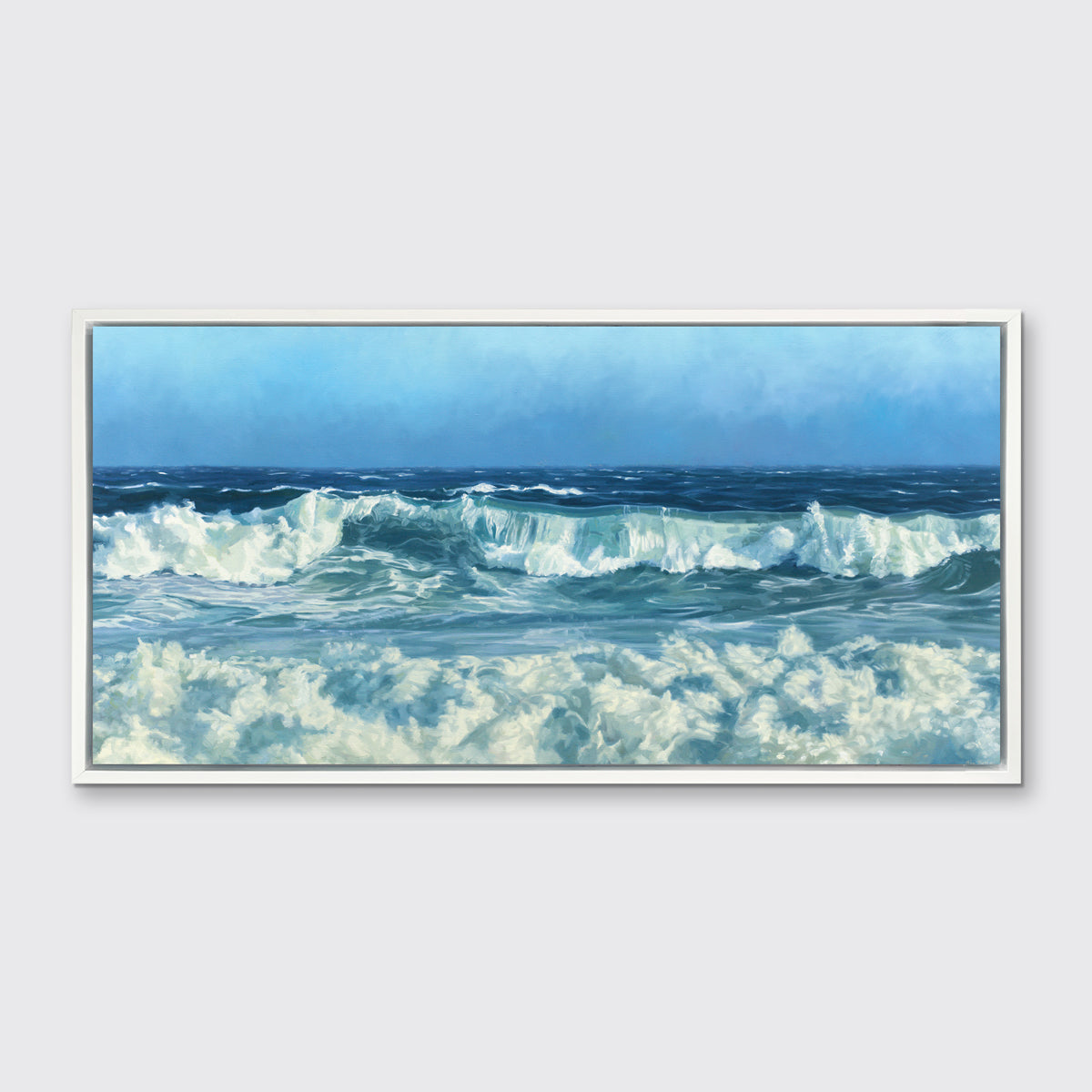 A blue and white seascape print in a white floater frame hangs on a white wall.