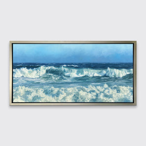 A blue seascape print in a silver floater frame hangs on a white wall.