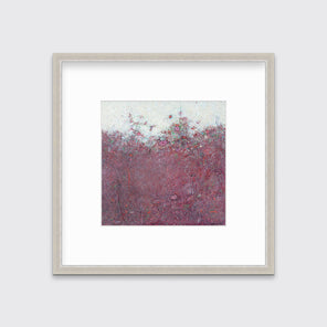 A dark red abstract landscape print in a silver frame with a mat hangs on a white wall.