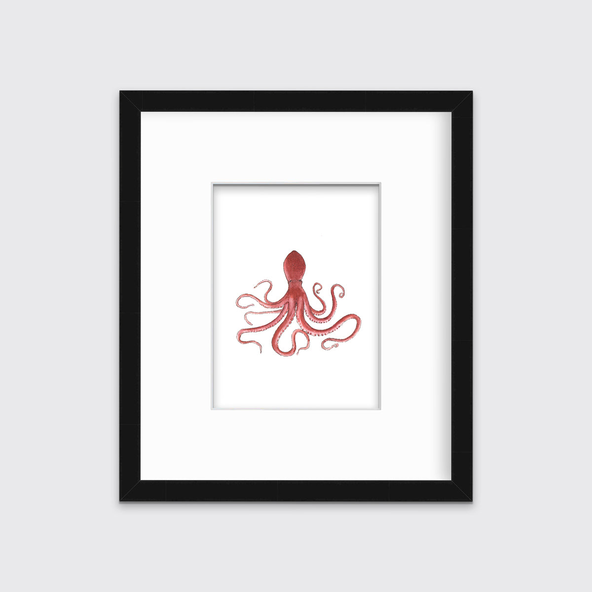 A pink octopus print in a black frame with a mat hangs on a white wall.