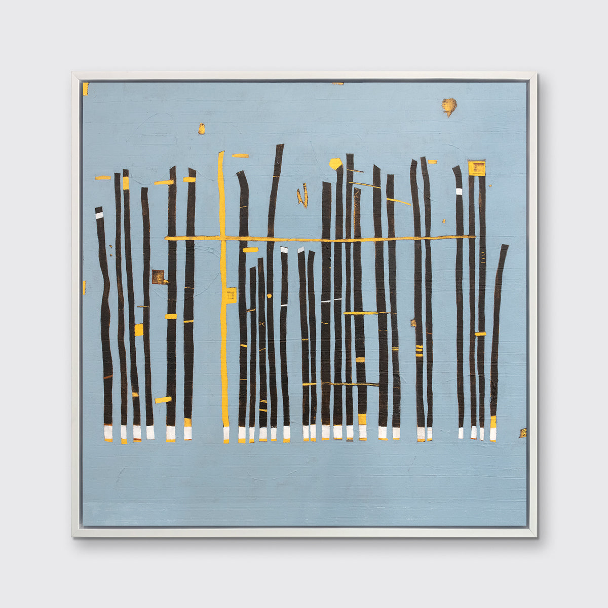 A blue, black and yellow abstract print in a white floater frame hangs on a white wall.