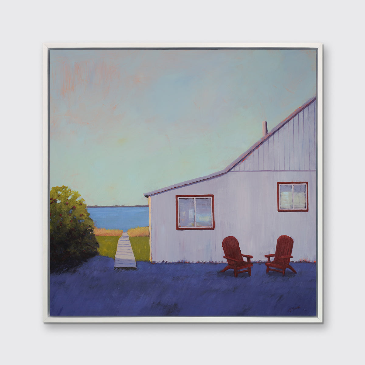 A blue, lavender and light purple contemporary seascape print with a beach house, two red adirondack chairs and a walkway leading to the water in a white floater frame hangs on a white wall.