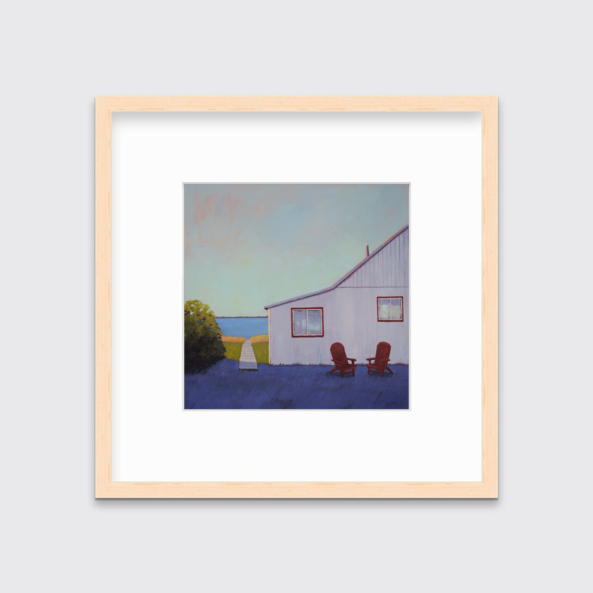 A blue, lavender and light purple contemporary seascape print with a beach house, two red adirondack chairs and a walkway leading to the water in a natural wood frame with a mat hangs on a white wall.