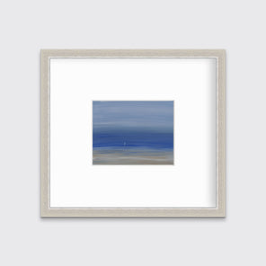 A blue and beige abstract seascape print in a silver frame with a mat hangs on a white wall.