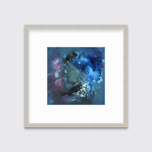 A blue, red, black and green abstract print in a silver frame with a mat hangs on a white wall.