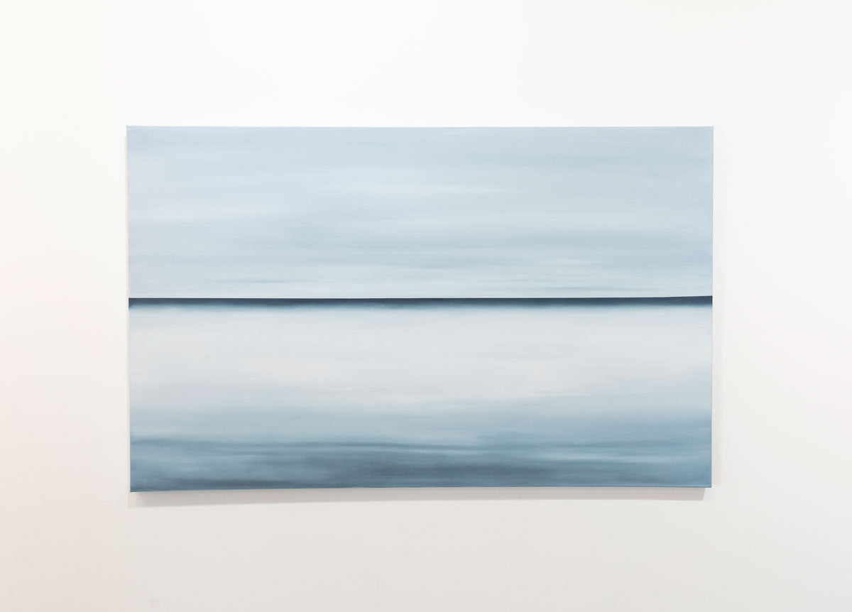 A blue oil painting with a single navy line in the middle of the canvas that suggests a horizon line is hung on a gallery wall. Wired and ready to hang.