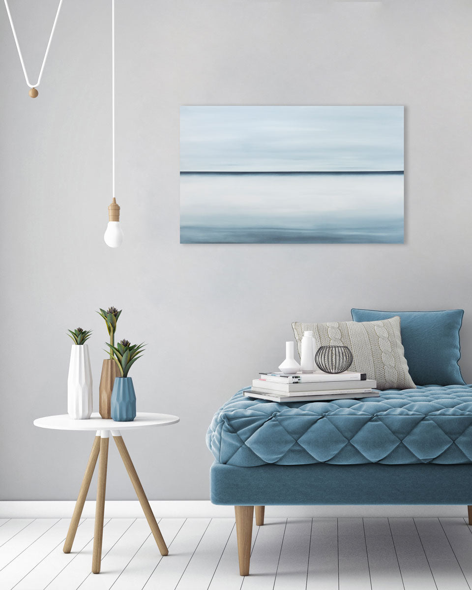 A blue oil painting with a single navy line in the middle of the canvas that suggests a horizon line is hung above furniture. Wired and ready to hang.