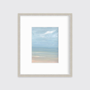 A white, blue and beige abstract seascape print in a silver frame with a mat hangs on a white wall.
