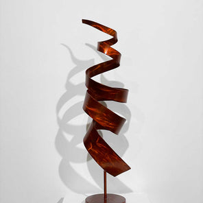 Spiral, abstract, steel sculpture, from the back view, with orange dye sitting on a pedestal in front of a white wall.