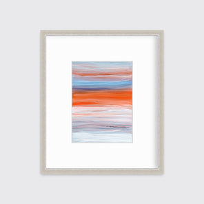 A blue, orange, light pink and white abstract print in a silver frame with a mat hangs on a white wall.