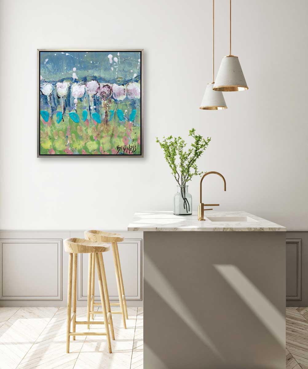 A teal, green and white abstract floral print in a silver floater frame hangs on a white wall above a white marble kitchen island with a sink and a small glass vase with greenery stems and two wood counter stools.