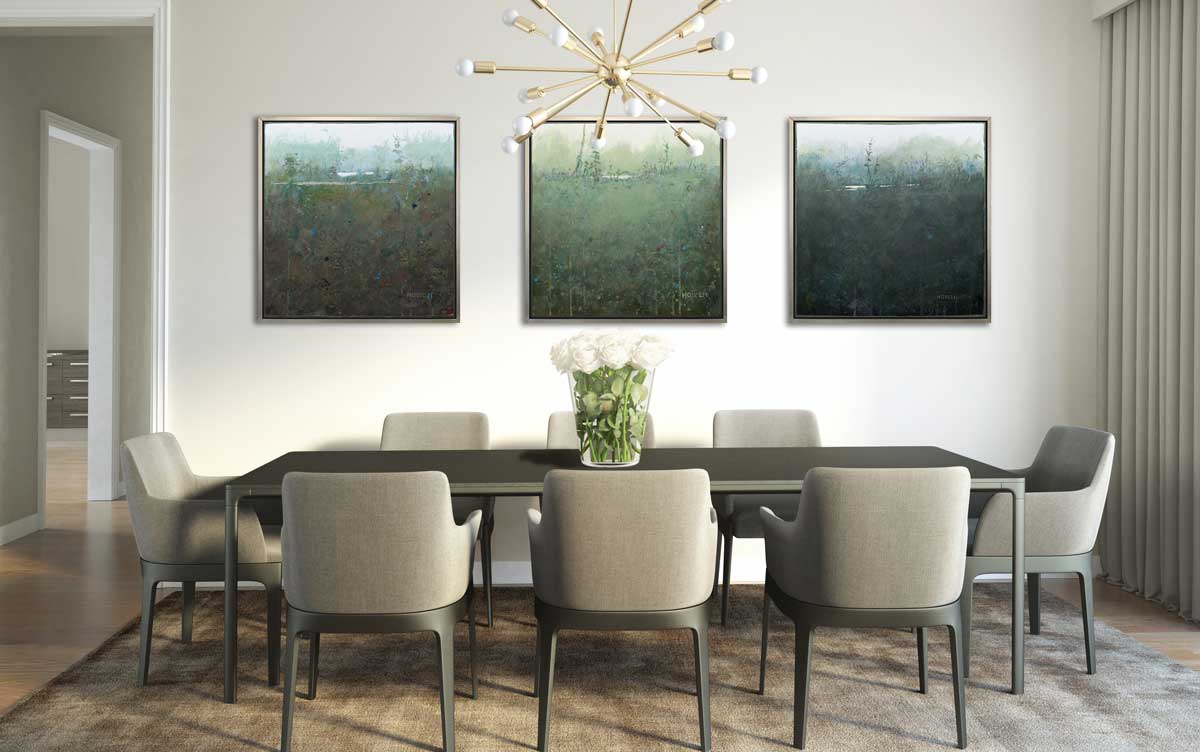 Three dark green abstract landscape prints in silver floater frames hang side by side on a white wall above a black dining table with eight grey chairs.