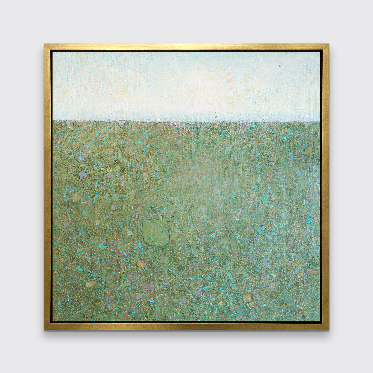 A green and blue abstract landscape print in a gold floater frame hangs on a white wall.