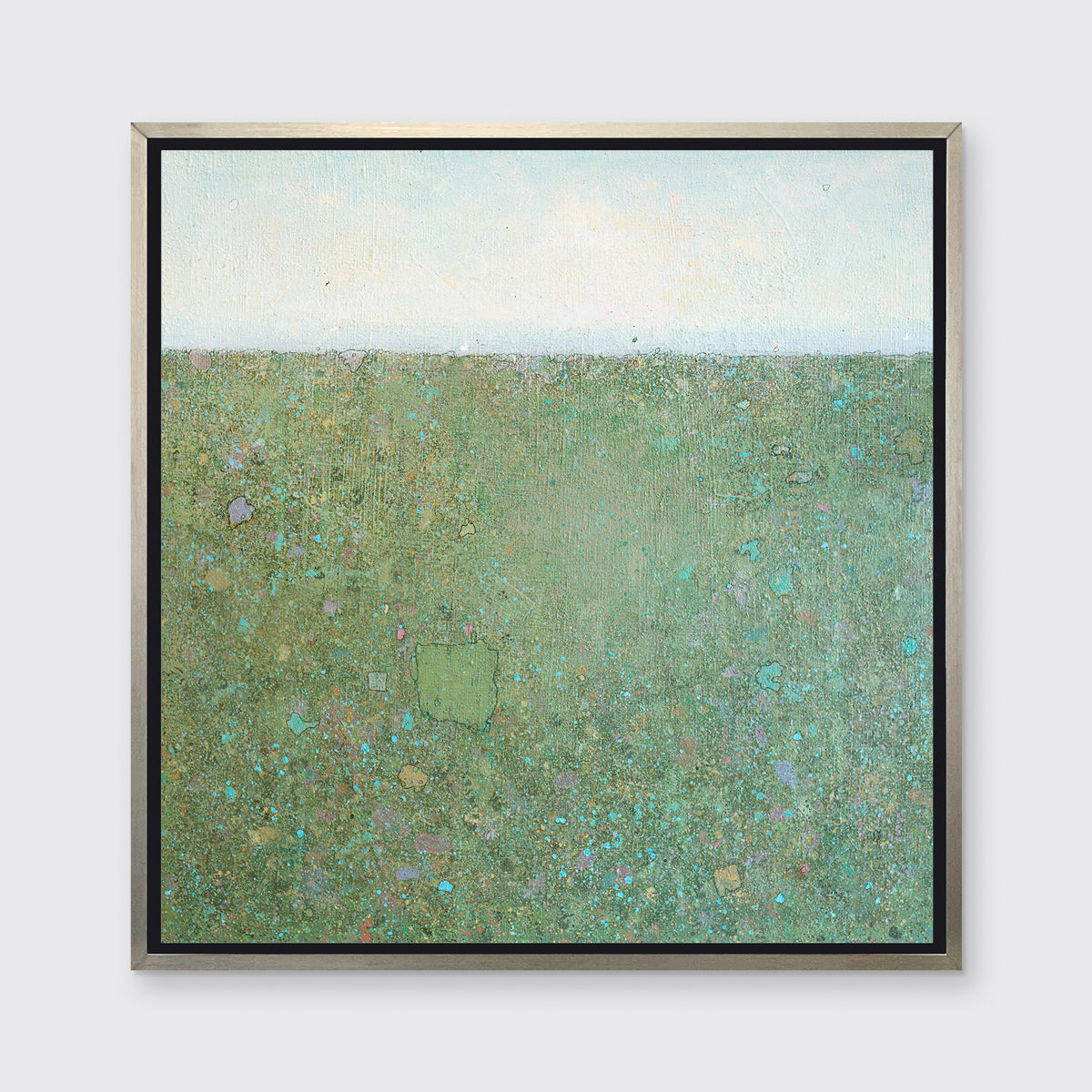 A green and blue abstract landscape print in a silver floater frame hangs on a white wall.