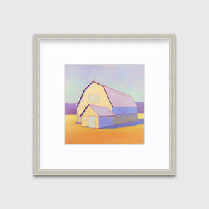 A lavender, light yellow and orange landscape print of a barn in a silver frame with a mat hangs on a white wall.