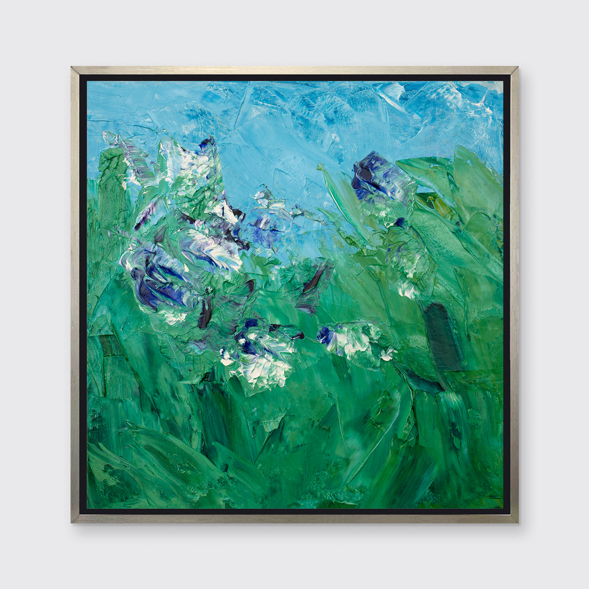 A blue, green, purple and white abstract landscape print in a silver floater frame hangs on a white wall.