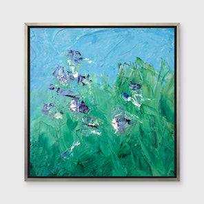 A blue, green, purple and white abstract landscape print in a silver floater frame hangs on a white wall.