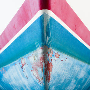 A close up photograph of a distressed bow from a red, white, and blue striped sailboat. 