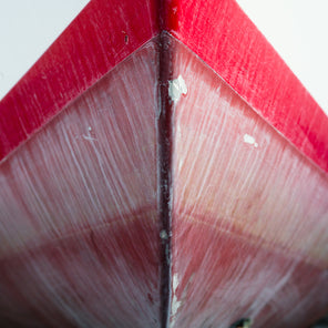 A close up photograph of a distressed bow from a red and white striped sailboat. 