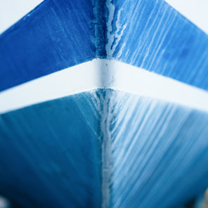 A close up photograph of a bow from a blue and white striped sailboat. 