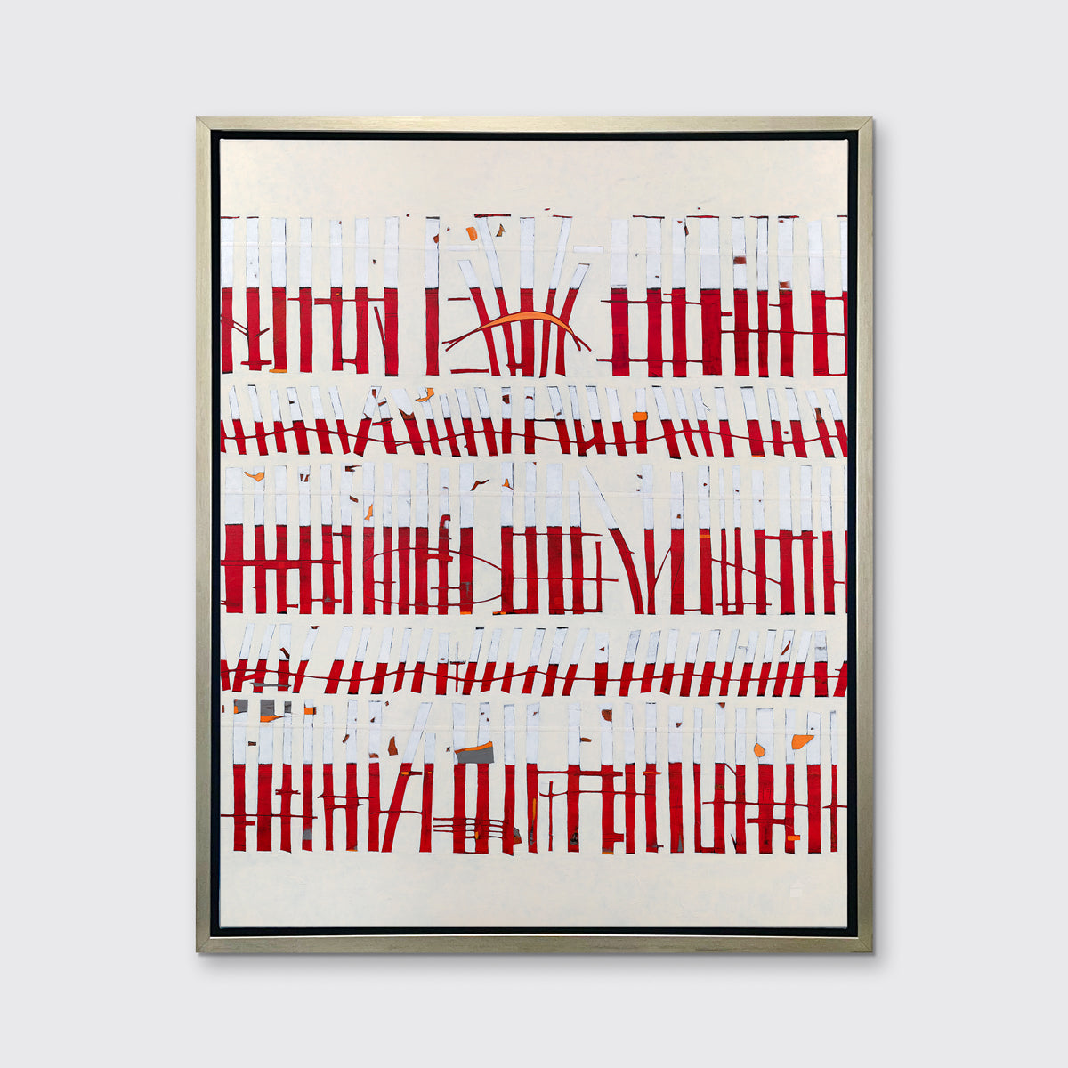 A beige, white and red abstract print in a silver floater frame hangs on a white wall.
