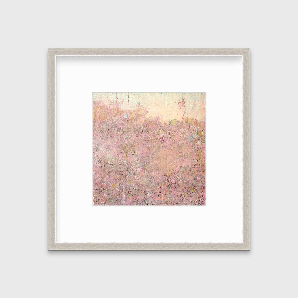 A pink abstract landscape print in a silver frame with a mat hangs on a white wall.