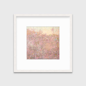 A pink abstract landscape print in a whitewashed frame with a mat hangs on a white wall.