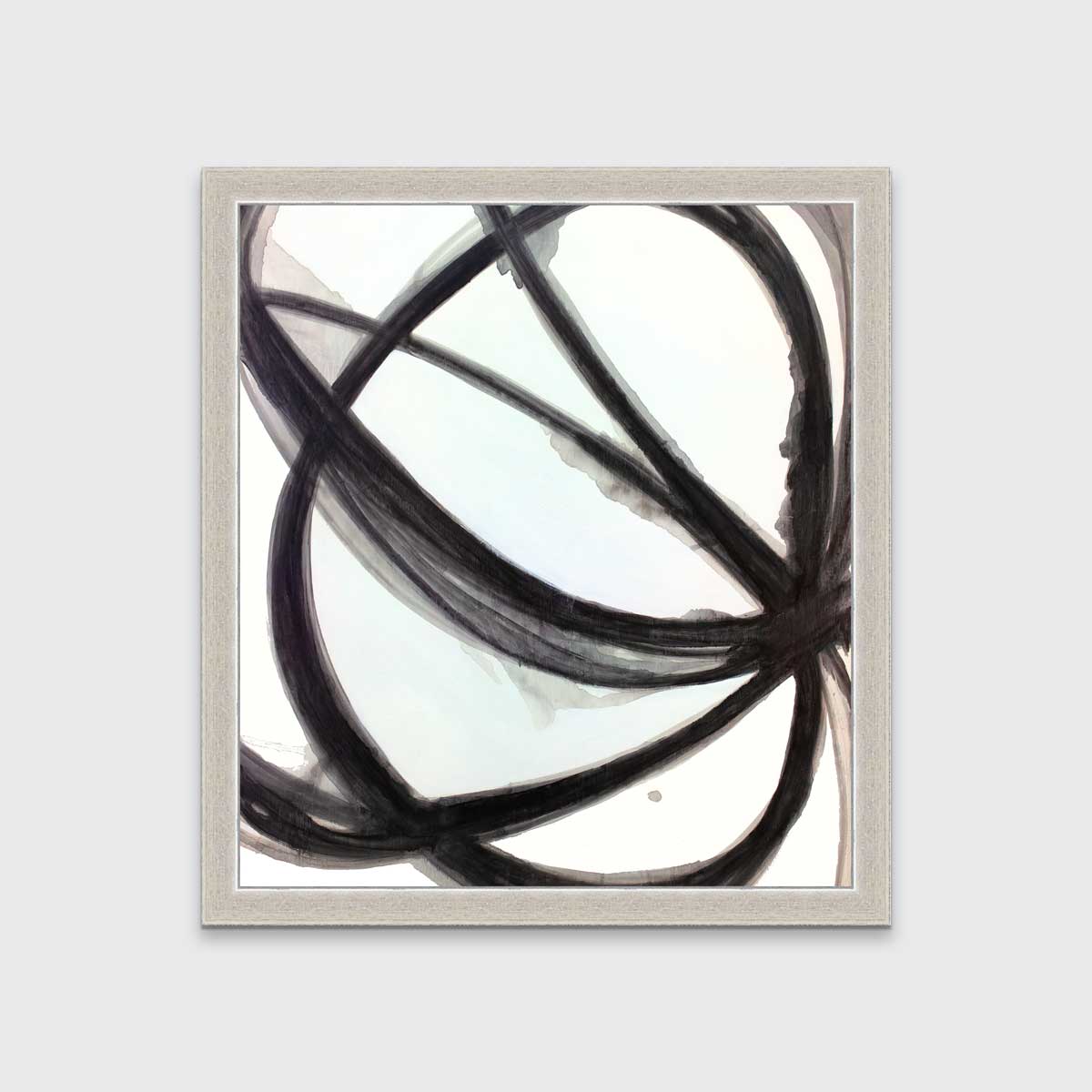 A black, grey and white abstract print in an unmatted silver frame hangs on a white wall.