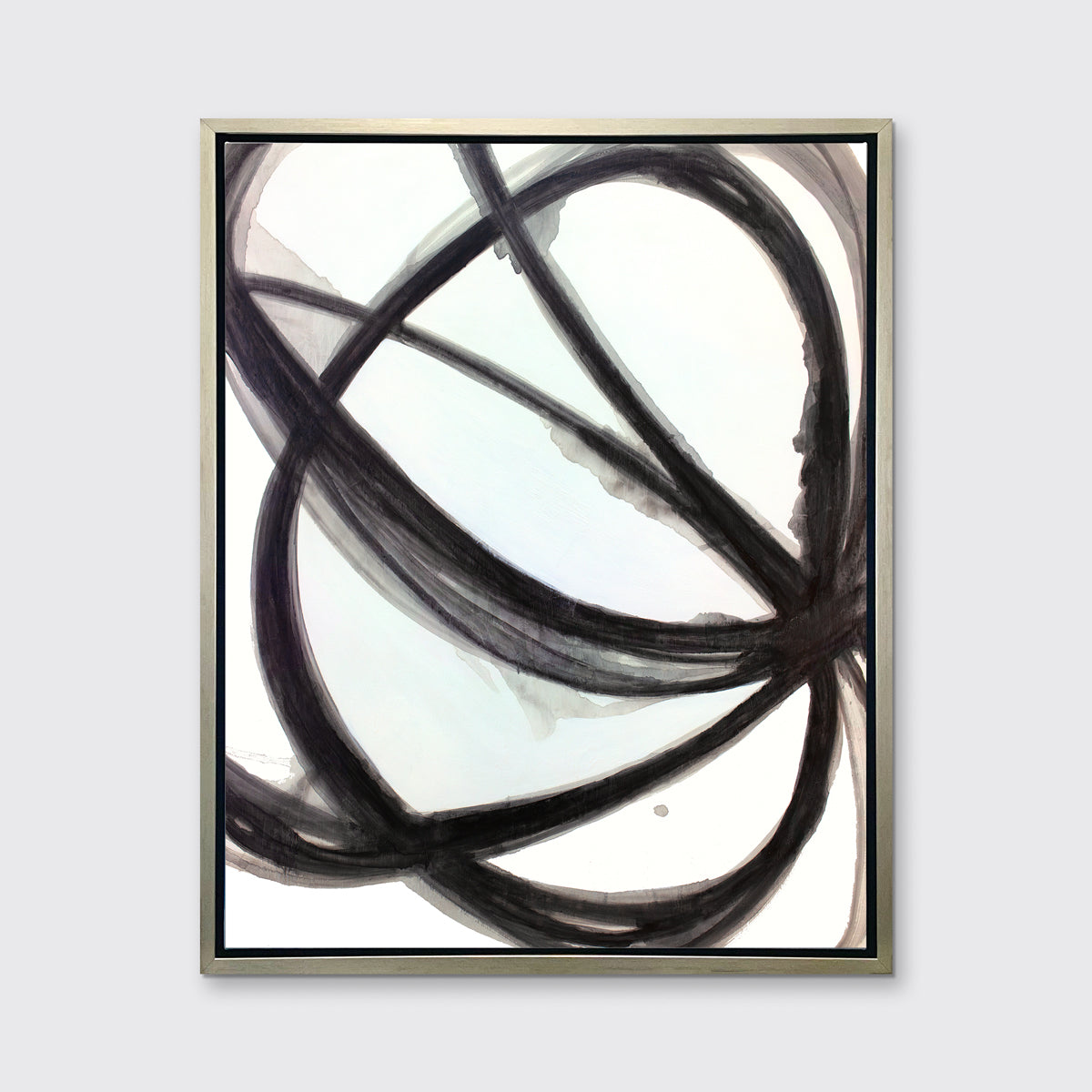 A black and white abstract canvas print framed in a warm silver frame, hangs on a light grey wall.