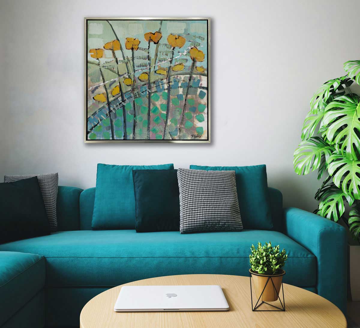 A blue, yellow, and green abstract floral painting hangs on a grey wall above a teal couch with black throw pillows, a wooden coffee table, and potted plants.