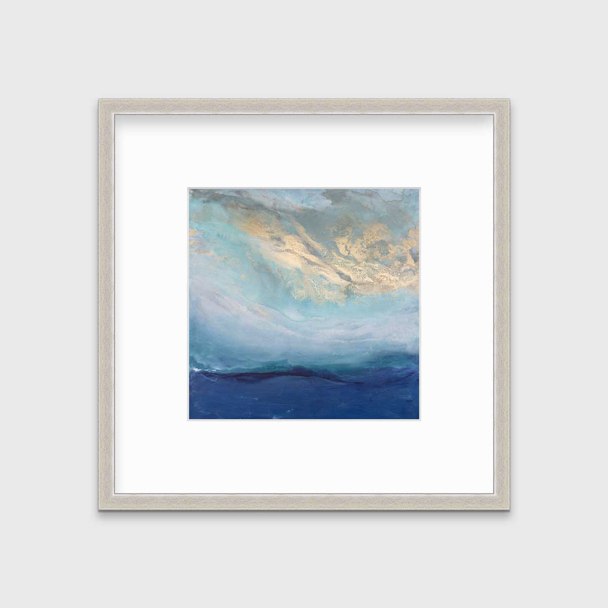 A blue, gold and teal abstract print in a silver frame with a mat hangs on a white wall.