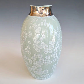 A light turquoise ceramic vessel with a 14k gold luster top and mini crystals in the glaze.