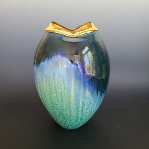 An oval abstract green and blue vase, with an 18k gold luster around the mouth of the vessel. 